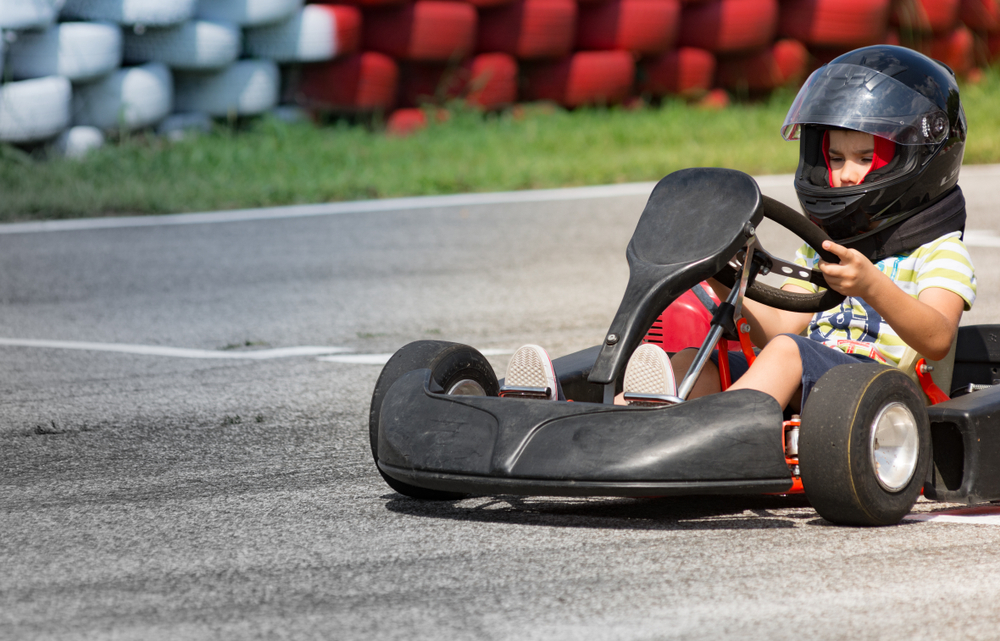 Child racing a go kart on a track.