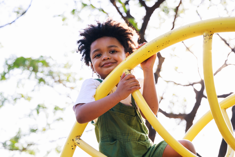 Child smiling while playing on a yellow playground