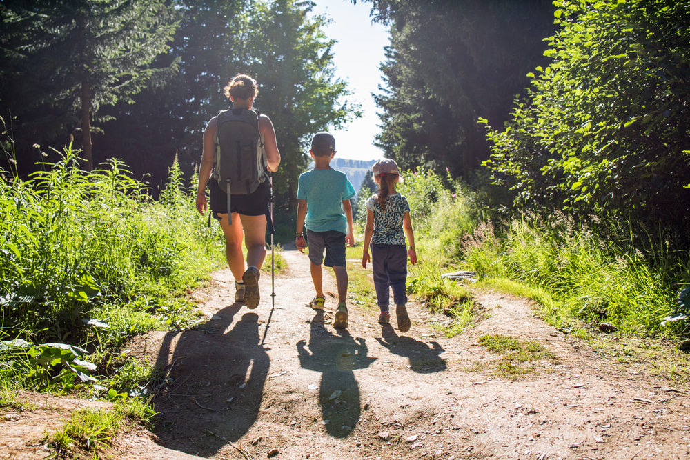 Family of three hiking on a trail.