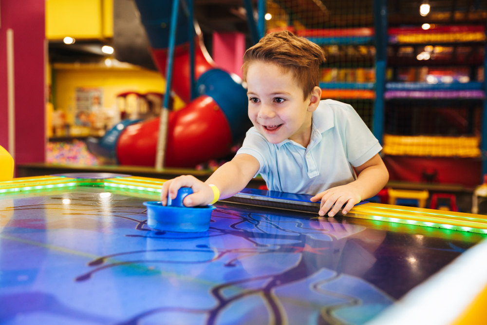 Little boy smiling while playing air hockey