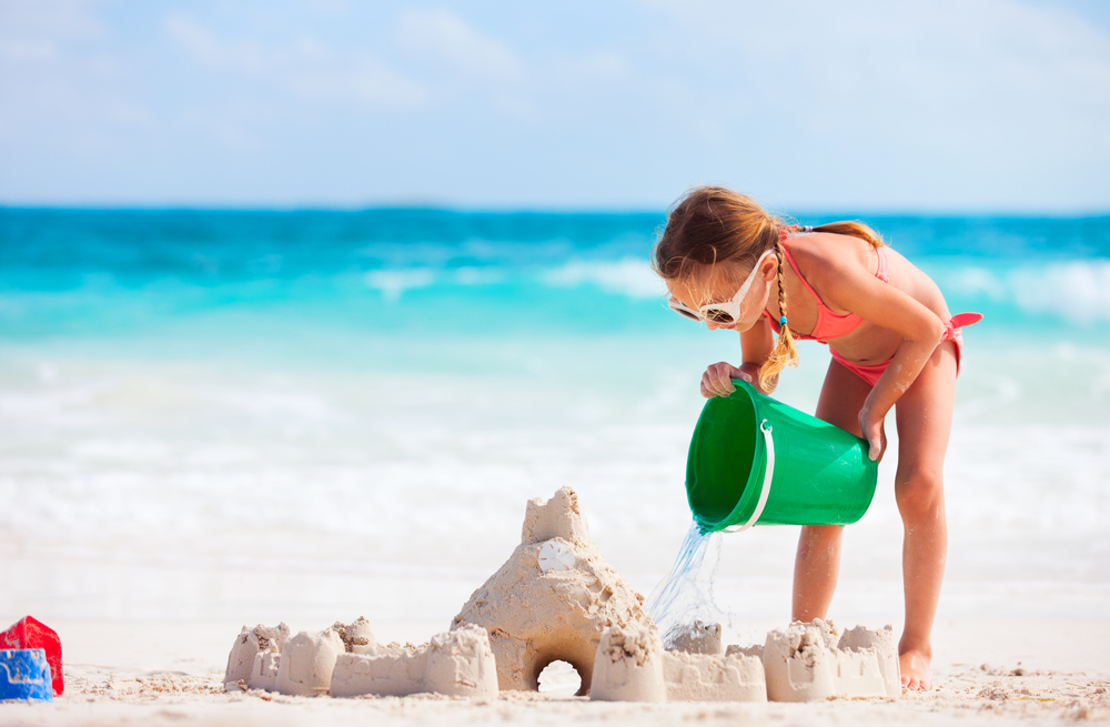 Little girl building a sand castle by the ocean