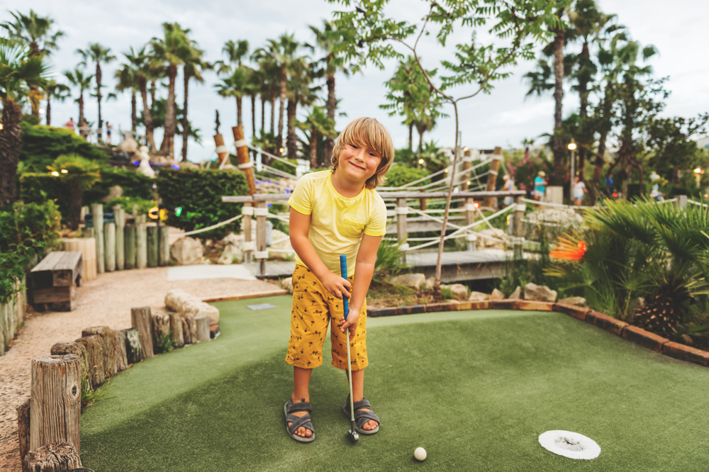 Kid smiling while playing mini golf