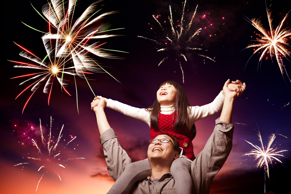 Father holding daughter under fireworks