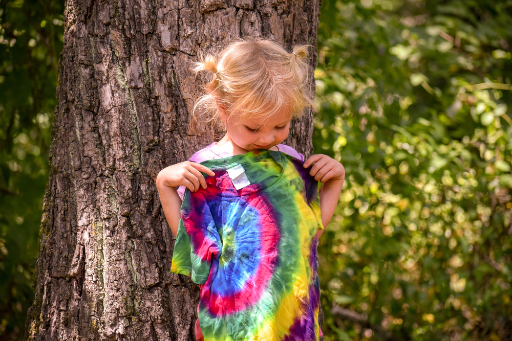 Little girl holding up a rainbow tie dye t shirt